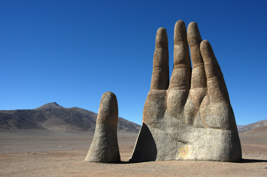 The Hand of the Desert statue in the Atacama Desert in Chile. Bright blue sky in the background.