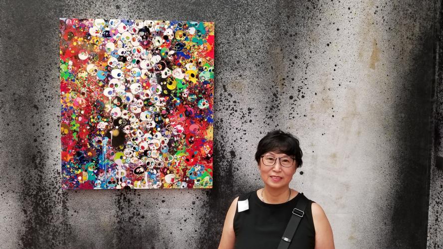 Tufts in Hong Kong director Vera Yip standing next to an abstract painting  