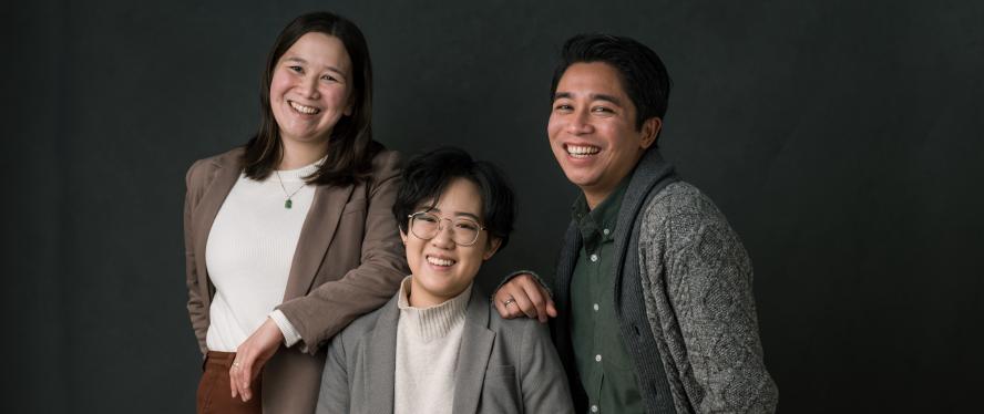 three people smiling and standing close to each other