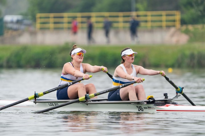 two students row on river in london