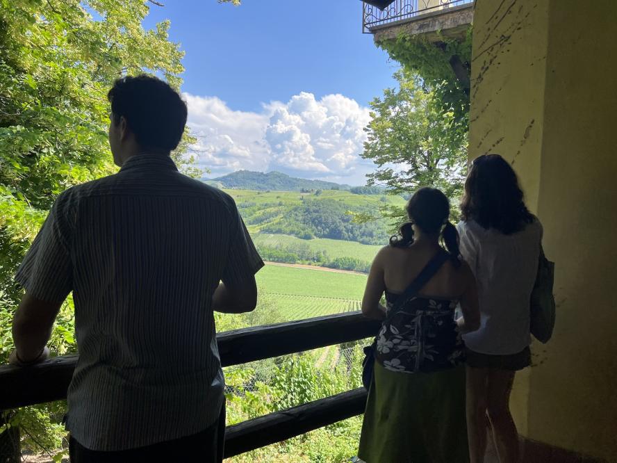 3 students stand on porch looking out at scenic view, pavia, italy
