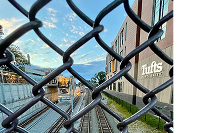 The MBTA tracks through a fence near Joyce Cummings Center.