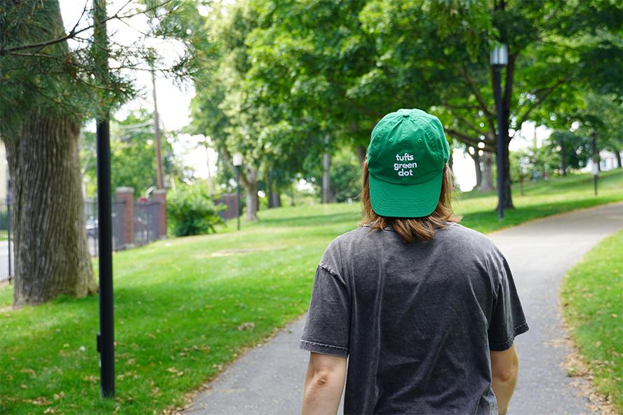 person walking across campus in Green Dot hat