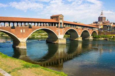 Ponte Coperto (Covered Bridge) in Pavia, Italy reflected in water below.